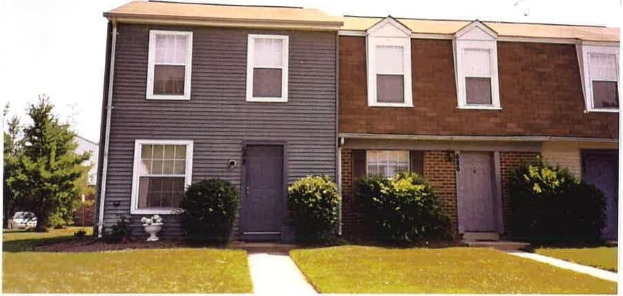 A row of two-story townhouses at Carroll LaPlata Village with brick and gray siding and private front doors