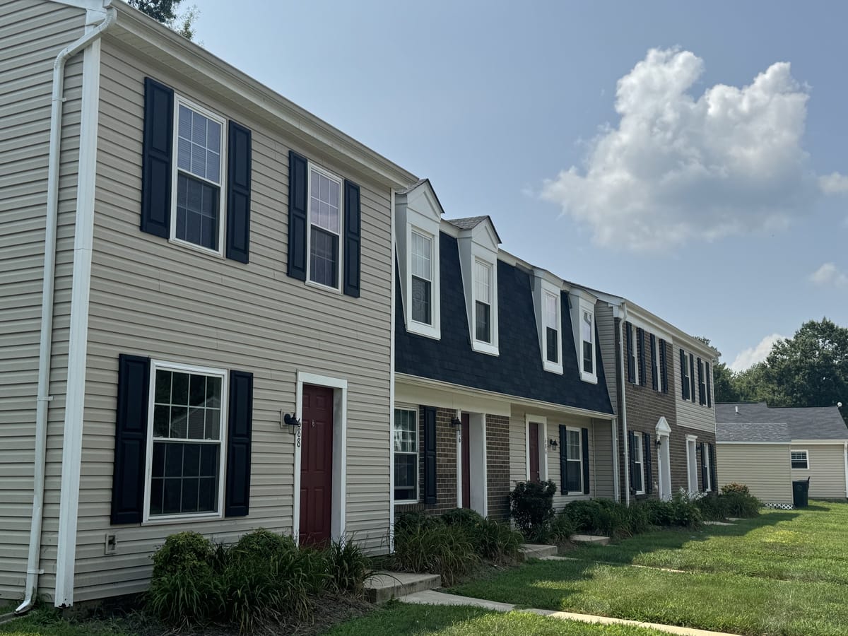 Looking down a row of townhouse entries at Carroll LaPlata Village, with red doors, black shutters and small front gardens