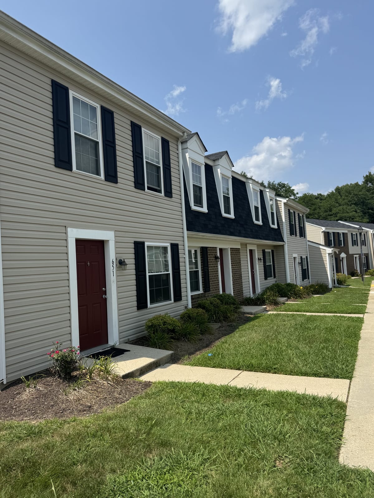A townhouse row at Carroll LaPlata Village seen along the front walk, with red doors and lawn